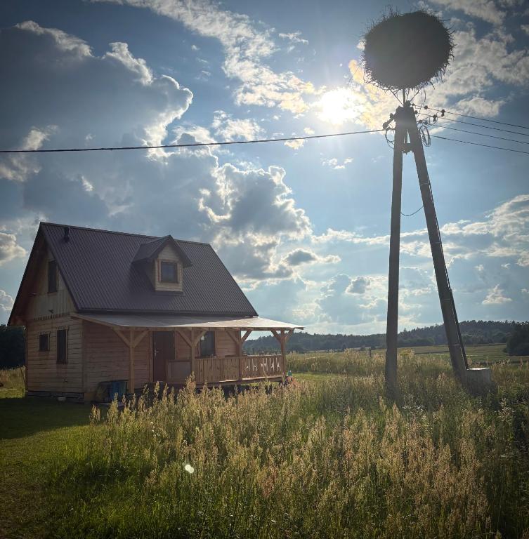 a house in a field next to a windmill at Bociani Zakątek nad jeziorem in Leszczewo