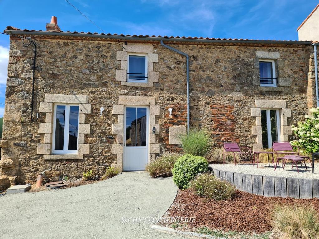ein Steinhaus mit einer Terrasse davor in der Unterkunft Maison de campagne HDH - Charme et moderne - Proche du Puy duFou in LʼÉpaux