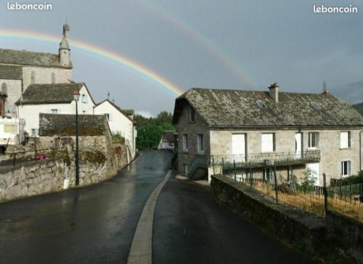 a rainbow in the sky over a street with buildings at Gîtes du Café de la poste in Le Buisson