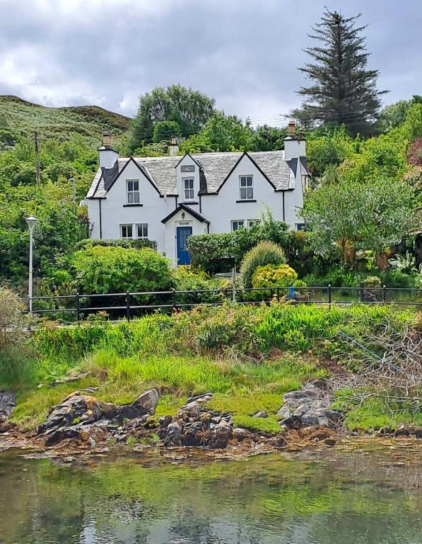 a white house on a hill next to a body of water at Hollybank, Kyleakin in Kyleakin