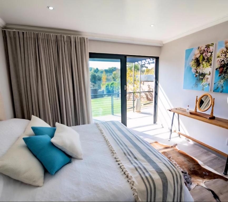 une chambre avec un grand lit avec des oreillers bleus dans l'établissement Rusgerus, à Pretoria