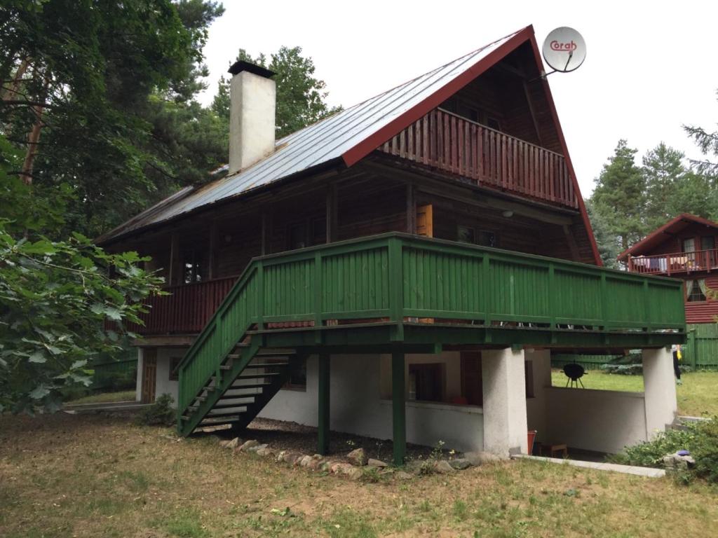 a large house with a green roof and stairs at Domek Letniskowy in Stare Jabłonki