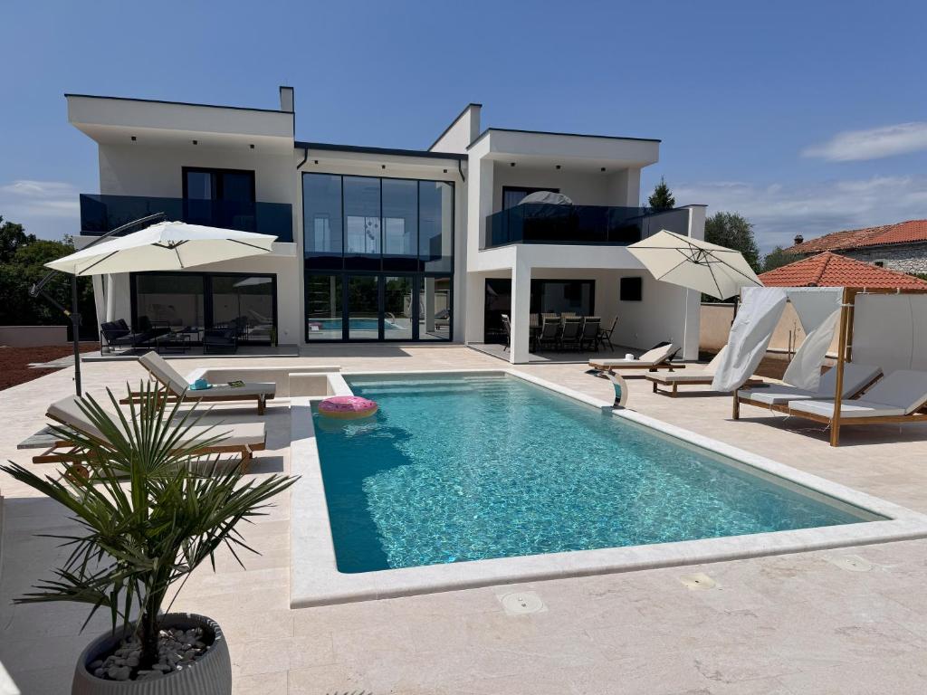 a villa with a swimming pool in front of a house at Villa Lustria in Labin