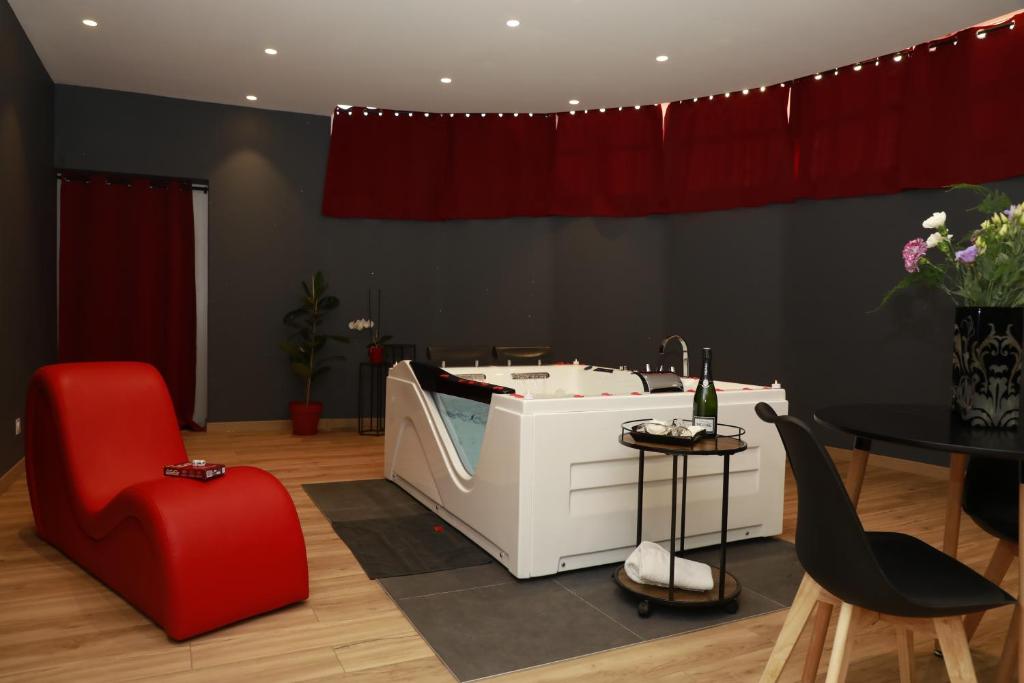 a bathroom with a bath tub and a red chair at La Suite Romantique in Rethel