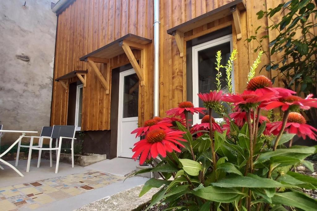 a house with red flowers in front of a building at Charmante maisonnette in Pontarlier