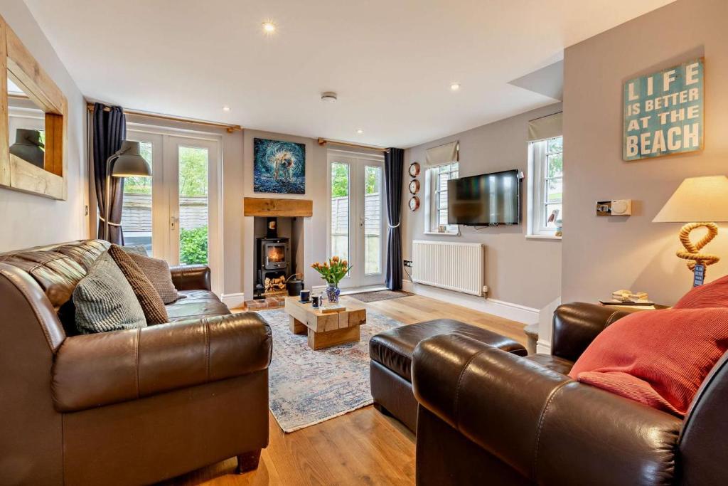 un salon avec un canapé en cuir et une télévision dans l'établissement Stamps Cottage - Uplyme, à Uplyme