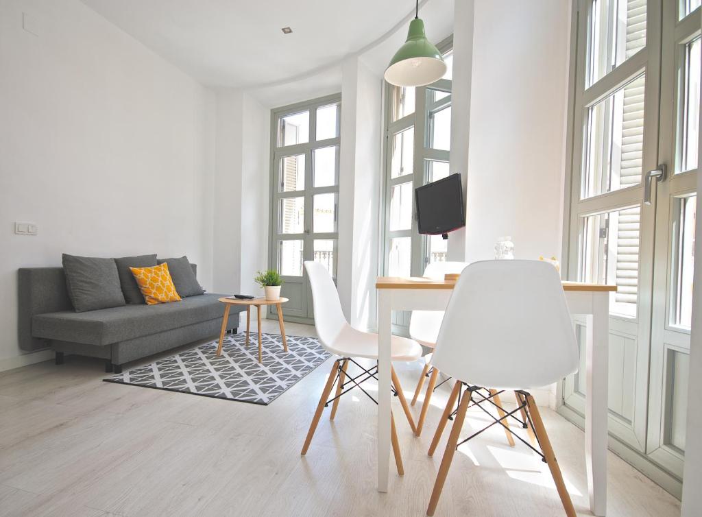 uma sala de estar com uma mesa e cadeiras brancas em MalagaUrbanRooms - Central Suites em Málaga