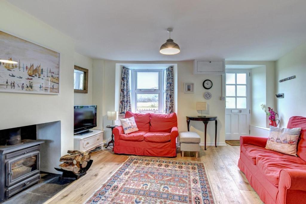 a living room with two red couches and a tv at Meadow Cottage in Bridport