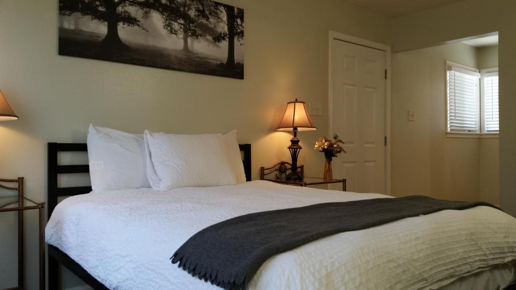 a bedroom with a white bed with a black blanket at Trees Motel in Bishop