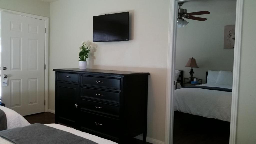 a bedroom with a dresser with a tv on the wall at Trees Motel in Bishop