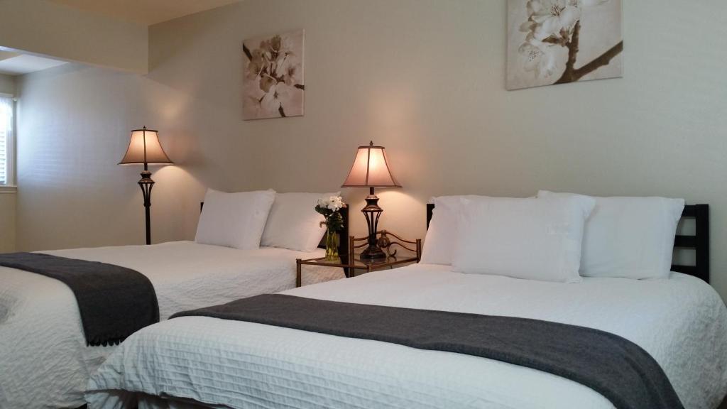 two beds in a room with two lamps at Trees Motel in Bishop