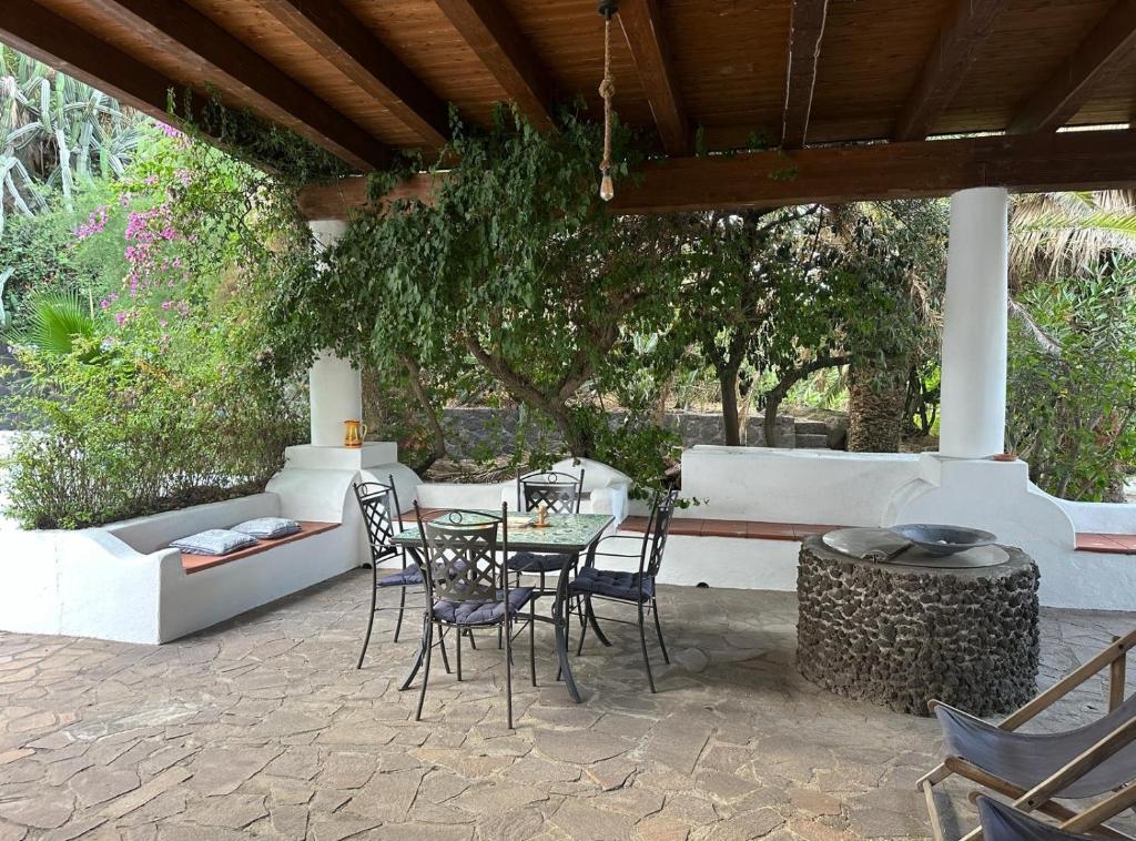 a patio with a table and chairs under a wooden roof at Schicciolina in Stromboli