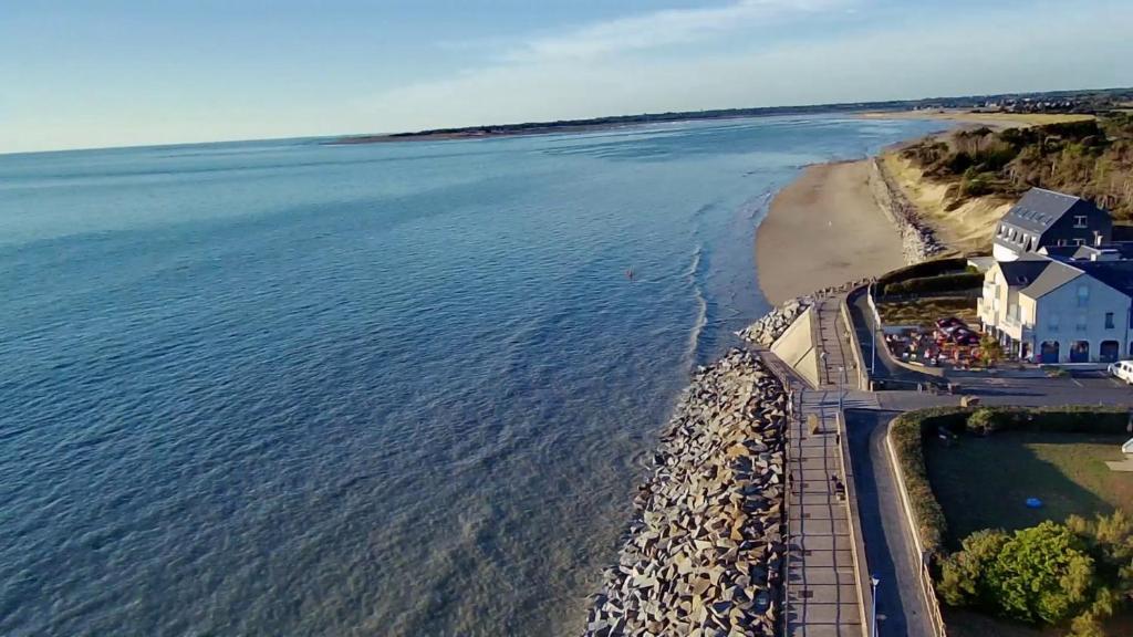 - une vue aérienne sur une plage avec une maison et l'eau dans l'établissement Bleu Soleil, à Hauteville-sur-Mer
