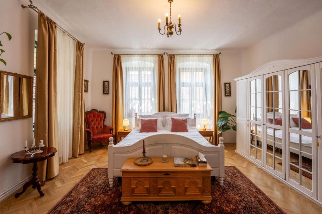 une chambre avec un lit blanc et une table dans l'établissement Breithofer Cottage Sighisoara, à Sighişoara