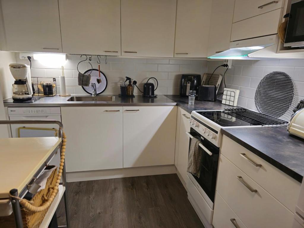 a kitchen with white cabinets and a stove top oven at 3room apartment at central Jyväskylä in Jyväskylä