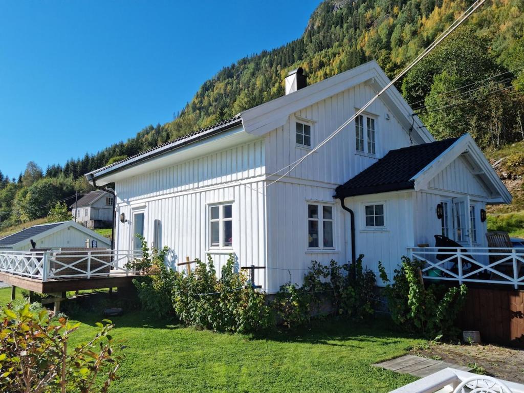 ein weißes Haus mit einem Berg im Hintergrund in der Unterkunft Great white cottage in Bygland in Bygland