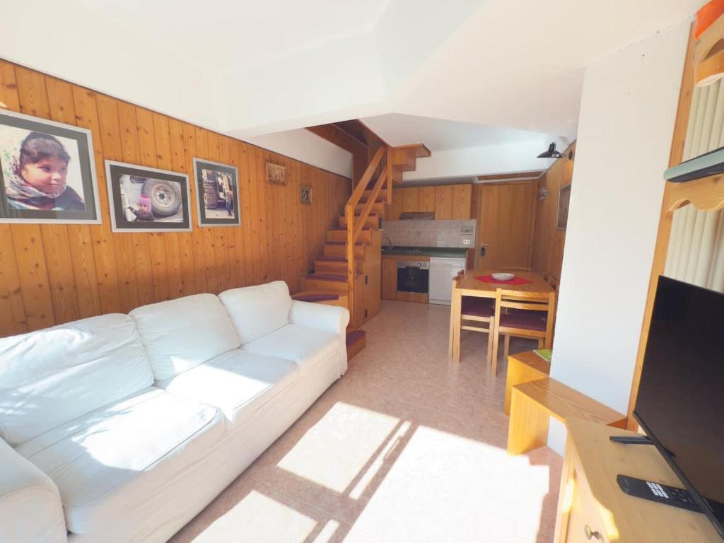a living room with a white couch and a staircase at Sole Alto Charm, Parking & Wi-Fi in Marilleva