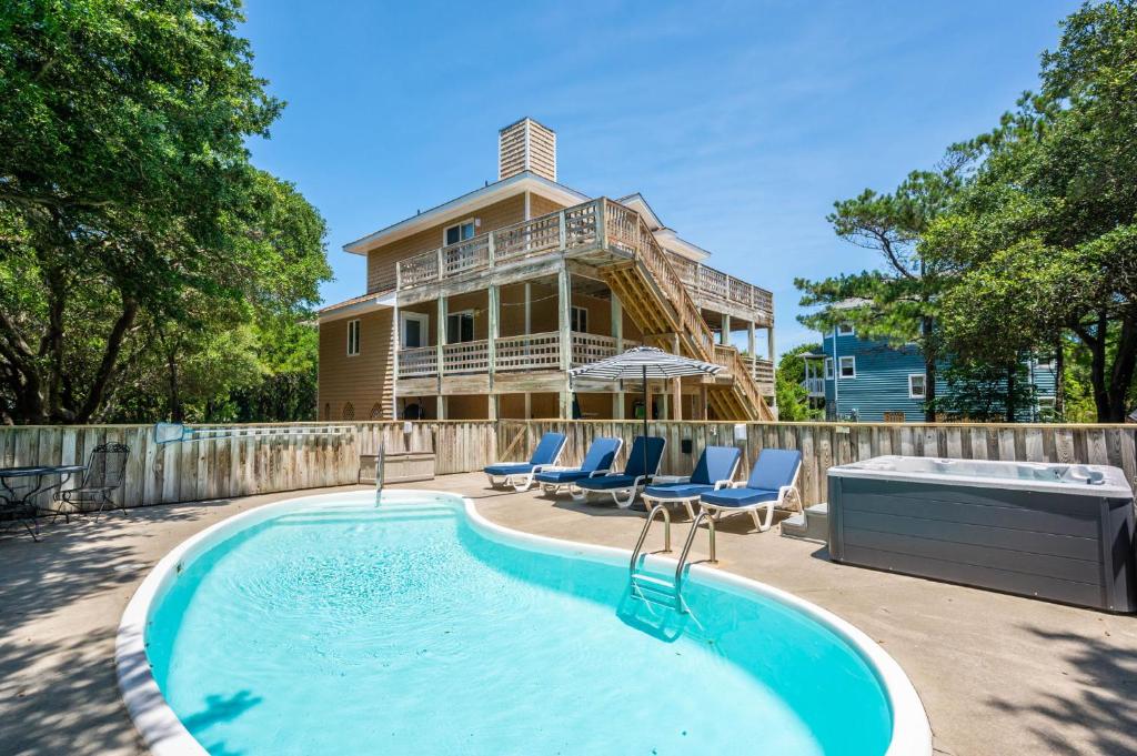 ein Haus mit einem Swimmingpool vor dem Haus in der Unterkunft Stylish Home with Pool Hot Tub & Walk to Beach in Duck