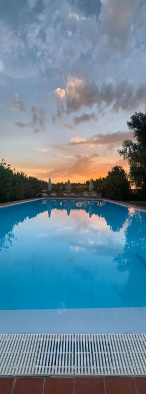 a large blue swimming pool with a sunset in the background at Podere San Pietro in Le Case