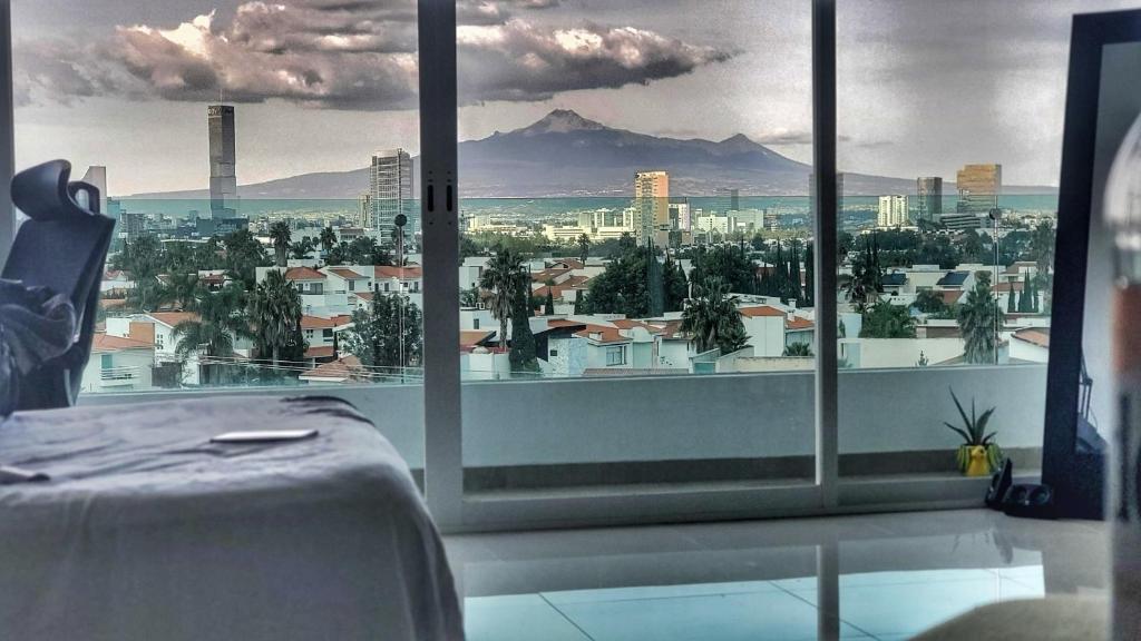 ein Zimmer mit einem großen Fenster mit Blick auf die Stadt in der Unterkunft Puebla Vista Malinche in Lomas de Angelopolis