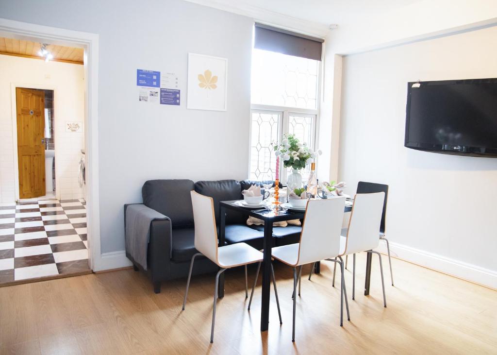 a dining room with a black table and white chairs at Modern, Spacious Home Ideal for Work Teams and Groups in Luton