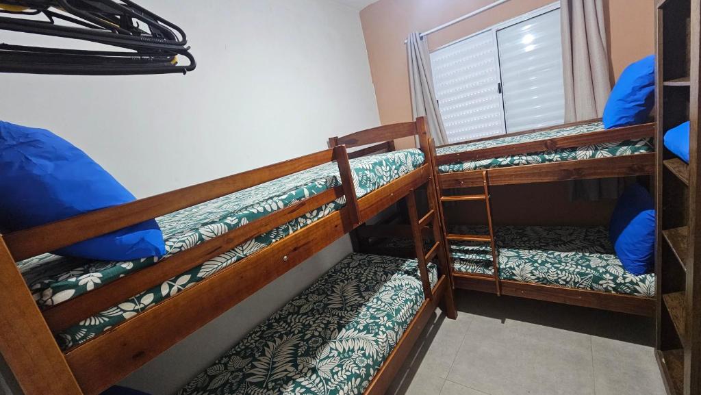 two bunk beds in a room with a window at Apto 2 quartos a 50 metros do Perequê in Ubatuba