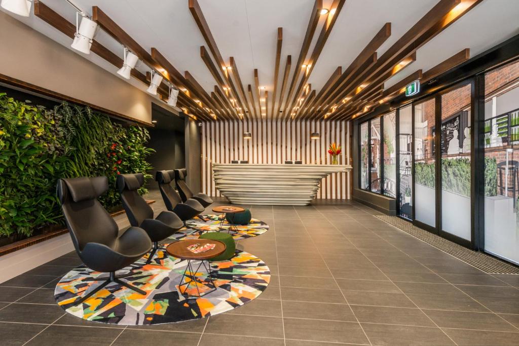 a lobby with a waiting area with chairs and plants at Kennigo Hotel Brisbane, Independent Collection by EVT in Brisbane