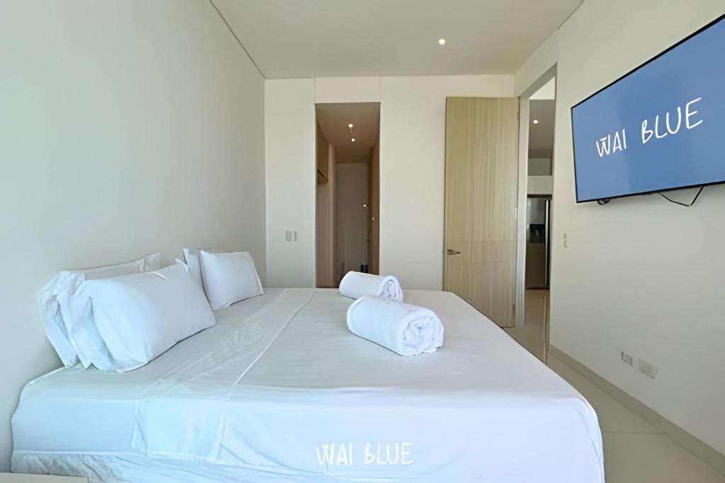 ein weißes Bett mit zwei Kissen und einem TV in der Unterkunft Wai Blue/Luxury Beachfront/ Bello Horizonte/ TTO03 in Playa Dormida