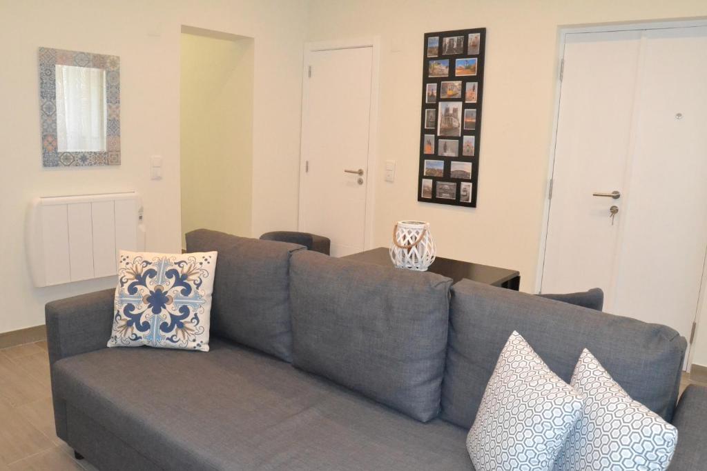 a living room with a gray couch with pillows at New charming flat in the Heart of Lisbon in Lisbon