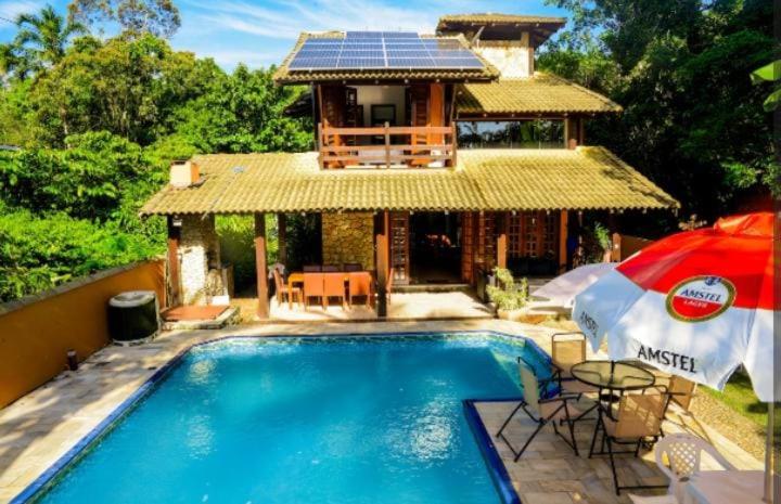 ein Haus mit Pool und ein Haus mit Sonnenschirm in der Unterkunft Casa Juréia com piscina aquecida, a 350m da praia - Litoral Norte in São Sebastião