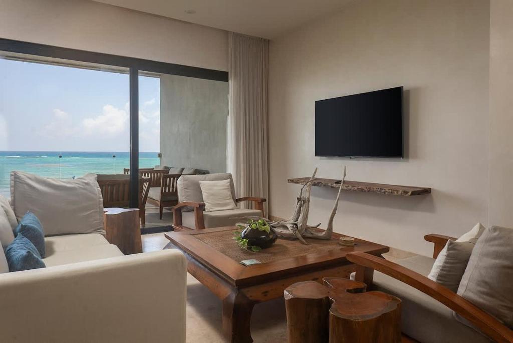 a living room with a couch and a table at 3BR Beachfront with Private Rooftop at Tankah Bay in Tulum