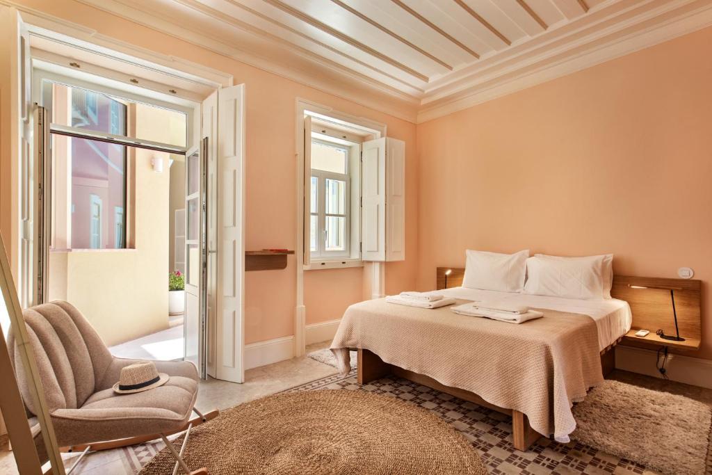ein Schlafzimmer mit einem Bett und einem Stuhl in der Unterkunft Palacete do Guadiana by MY CHOICE in Vila Real de Santo António