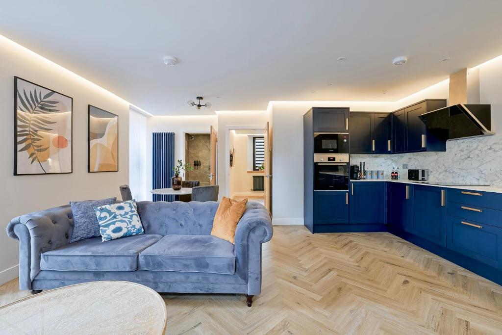 a living room with a blue couch and a kitchen at Modern apartment in town centre in Oban