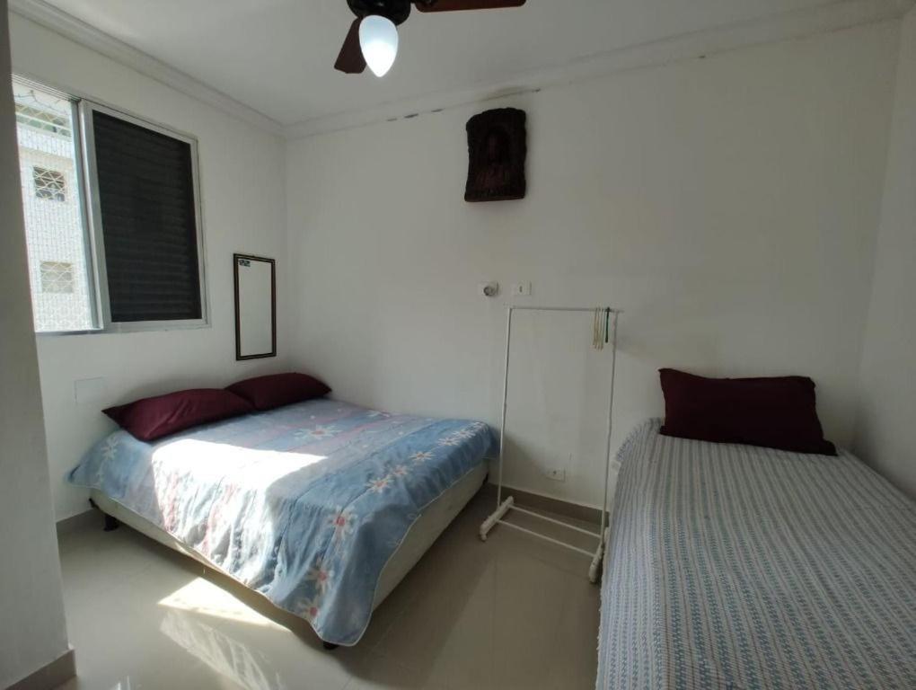 Un dormitorio con una cama al lado de una ventana. en Apê da Pê, en Praia Grande