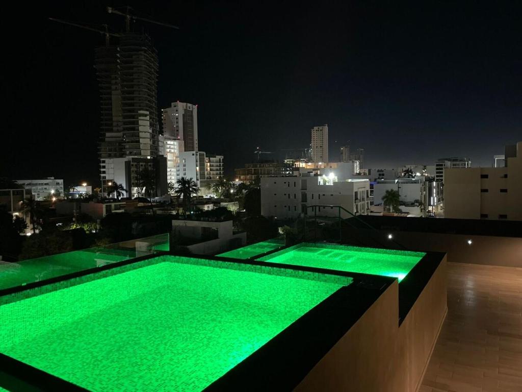 a green swimming pool on top of a building at night at Comfort stay Mazatlan in Mazatlán