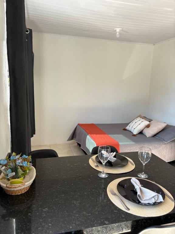 a room with a bed and two plates on a table at Loft casal - Centro de Bombinhas in Bombinhas