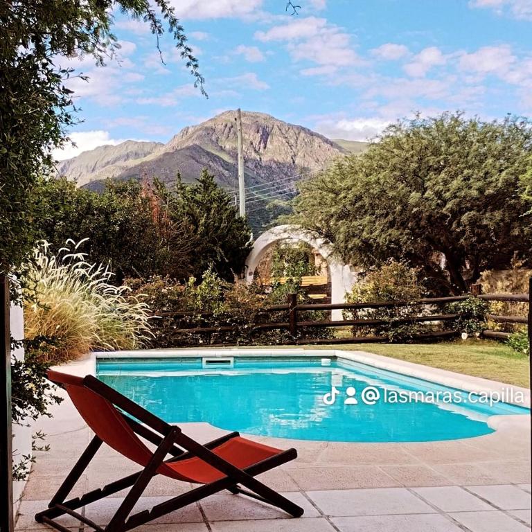 a chair next to a swimming pool with a mountain at Cabanas Las Maras in Capilla del Monte