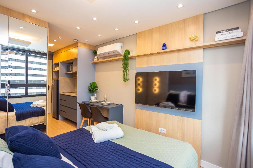 a bedroom with two beds and a desk and a kitchen at Apto no All Batel finamente mobiliado perto do shopping Curitiba in Curitiba