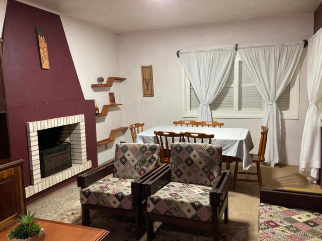 a living room with a table and chairs and a fireplace at Casa Planalto Gramado in Gramado