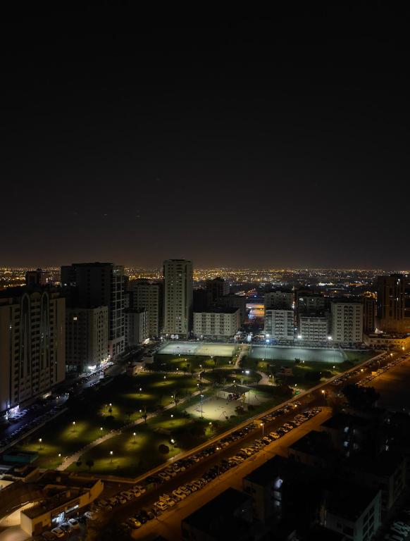 a city lit up at night with a parking lot at Luxury Rooms in Sharjah