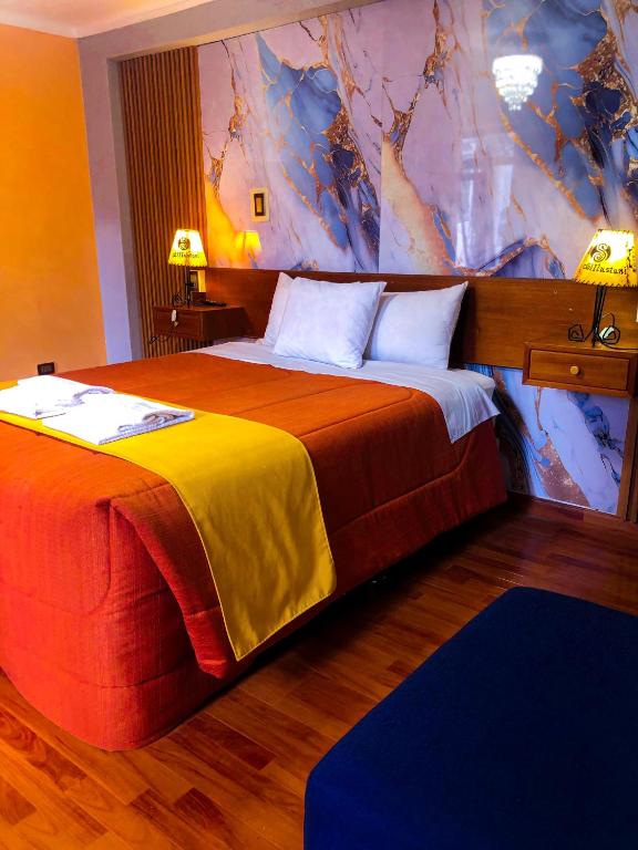 Una habitación de hotel con dos camas con sábanas naranjas y amarillas. en Hostel Sillustani Inn Puno, en Puno