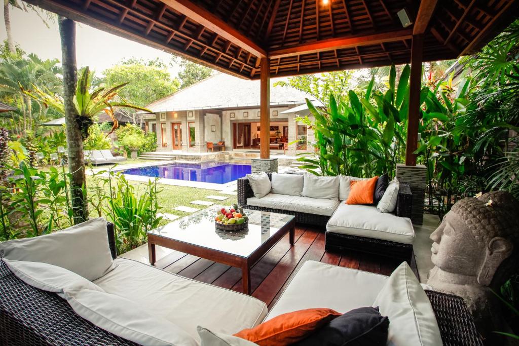 a patio with couches and a table and a pool at Villa Dewata in Seminyak