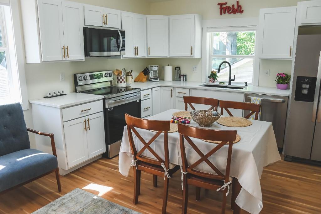 コー・ダレーンにあるModern, Quiet and Charming Downtown Apartmentの白いキャビネットとテーブルと椅子のあるキッチン