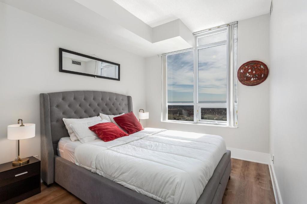 ミシサガにあるLavish 2BR 2Bath Condo Steps to Square One Mallのベッドルーム1室(赤い枕のベッド1台、窓付)