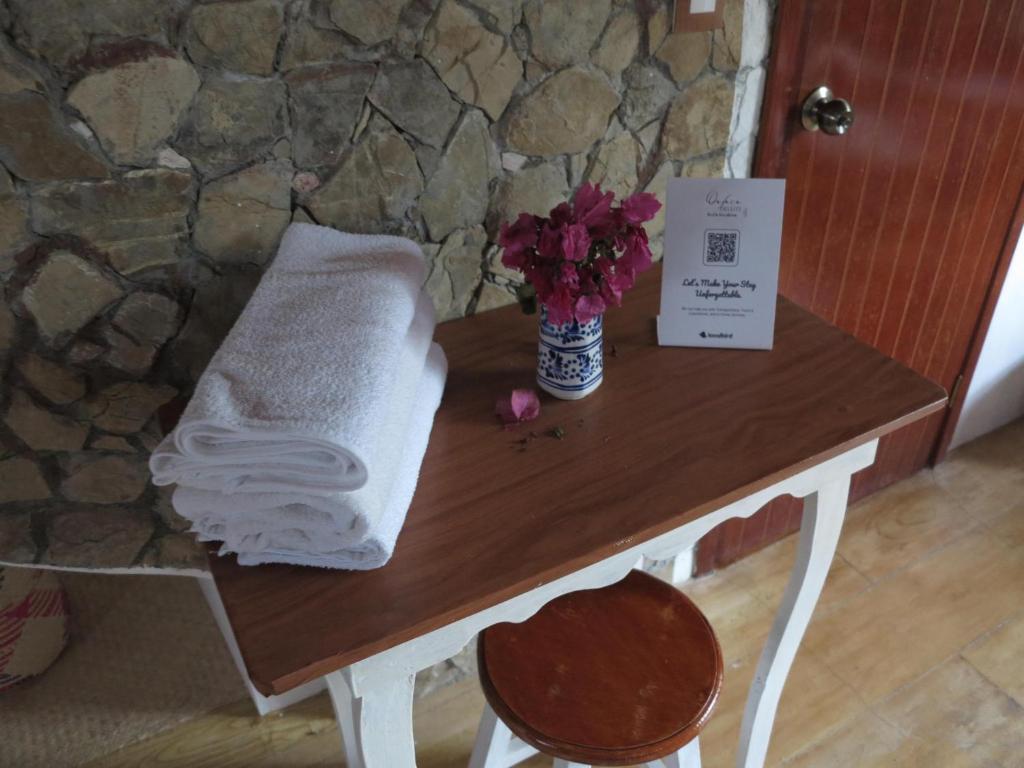 a table with a towel and a vase of flowers at Habitación doble con baño y vista a la montaña in San Pablo Etla