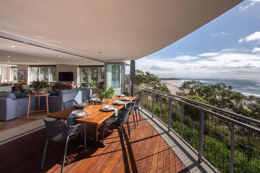 a balcony with a table and chairs and the ocean at Waves #14 Straddie Hotel in Point Lookout