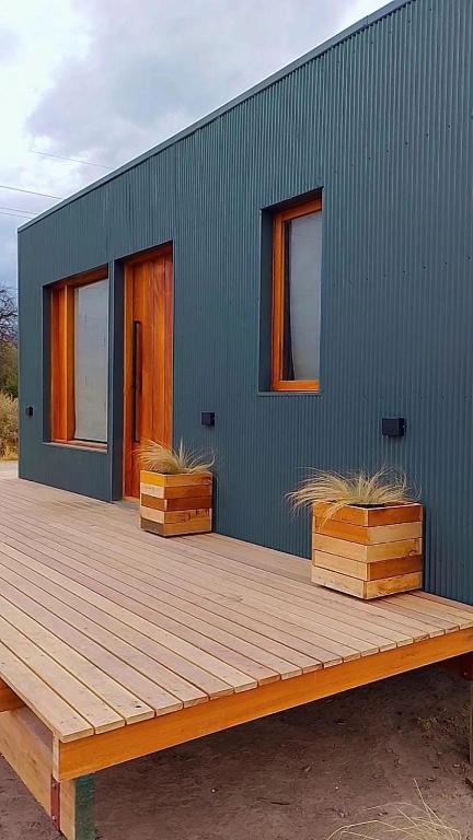 a green house with two boxes on a wooden deck at CJ cardones in Cafayate