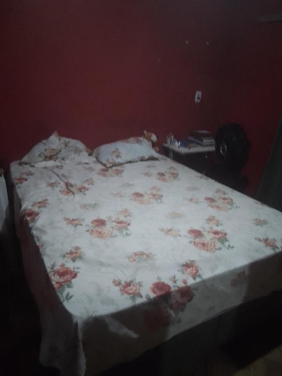 ein Bett mit einer weißen Decke mit rosa Blumen drauf in der Unterkunft Casa do Wellington bairro curuçambá Ananindeua in Ananindeua