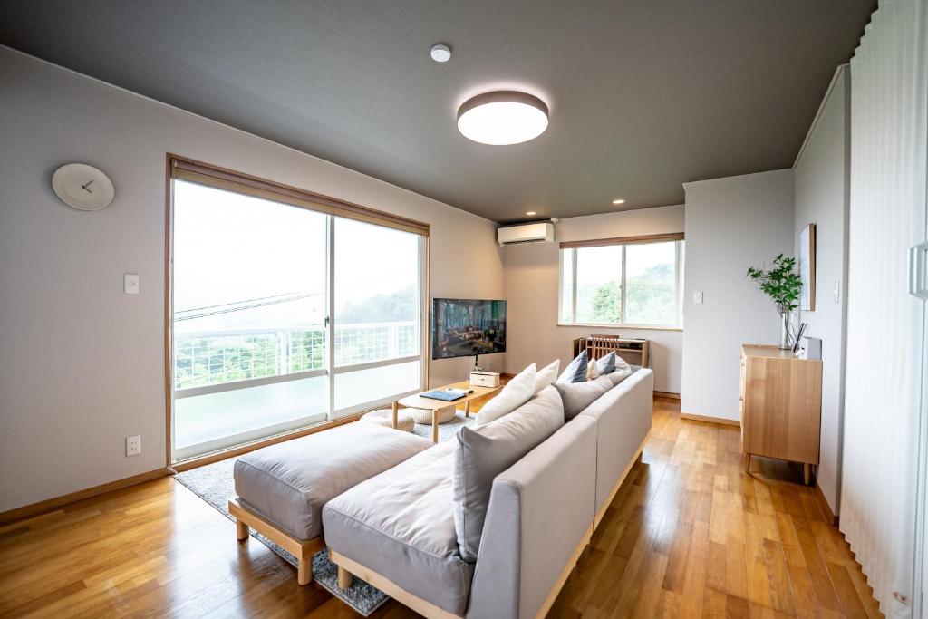 雾岛市貸切温泉宿 Shiny inn Kirishimaシャイニーイン霧島的客厅配有白色沙发和大窗户