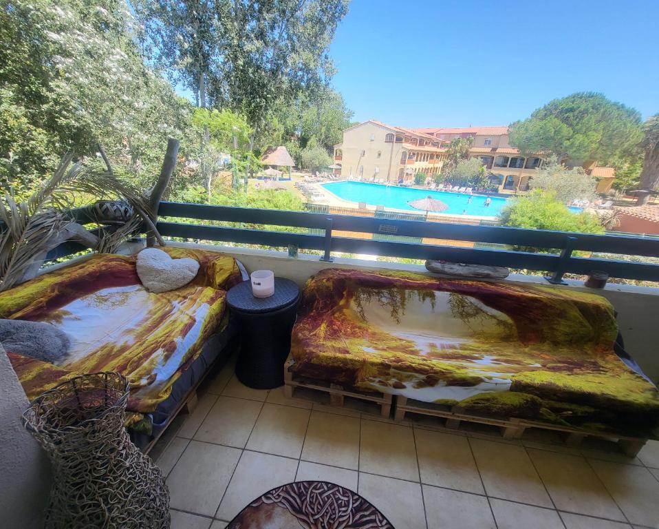 un balcon avec deux lits et une vue sur une piscine dans l'établissement Petit paradis du 66,Canet Roussillon, à Canet
